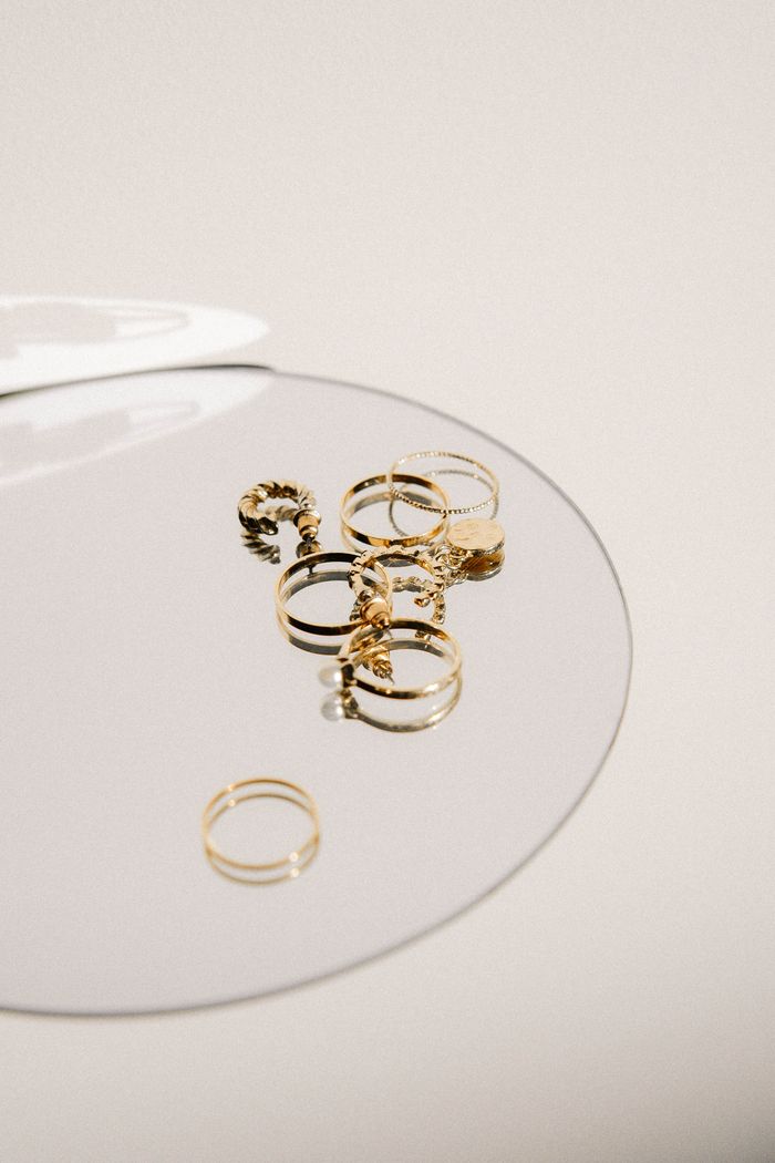 Stylish collection of gold rings displayed on a reflective surface for luxury appeal.