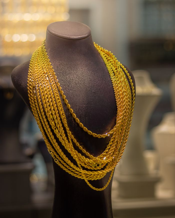 Luxurious gold necklace showcased on a mannequin in a jewelry store, highlighting elegance and style.